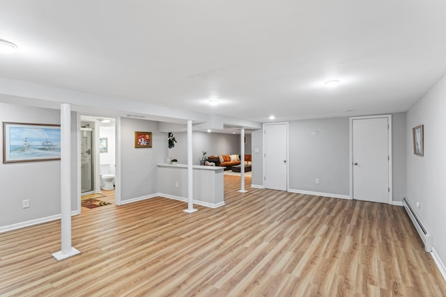 basement with baseboard heating and light hardwood / wood-style floors