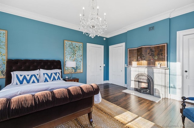 114 Walkley Hill Rd, Haddam, CT 06438 - bedroom with a chandelier, wood finished floors, crown molding, a fireplace with flush hearth, and two closets
