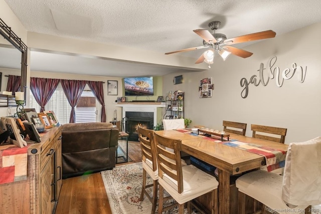 dining area with ceiling fan, hardwood / wood-style floors, and a textured ceiling