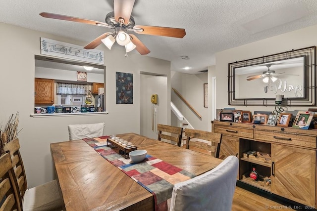 dining room with ceiling fan, a textured ceiling, and light hardwood / wood-style flooring