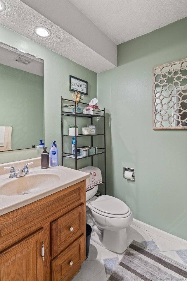 bathroom featuring toilet, vanity, tile patterned flooring, and a textured ceiling