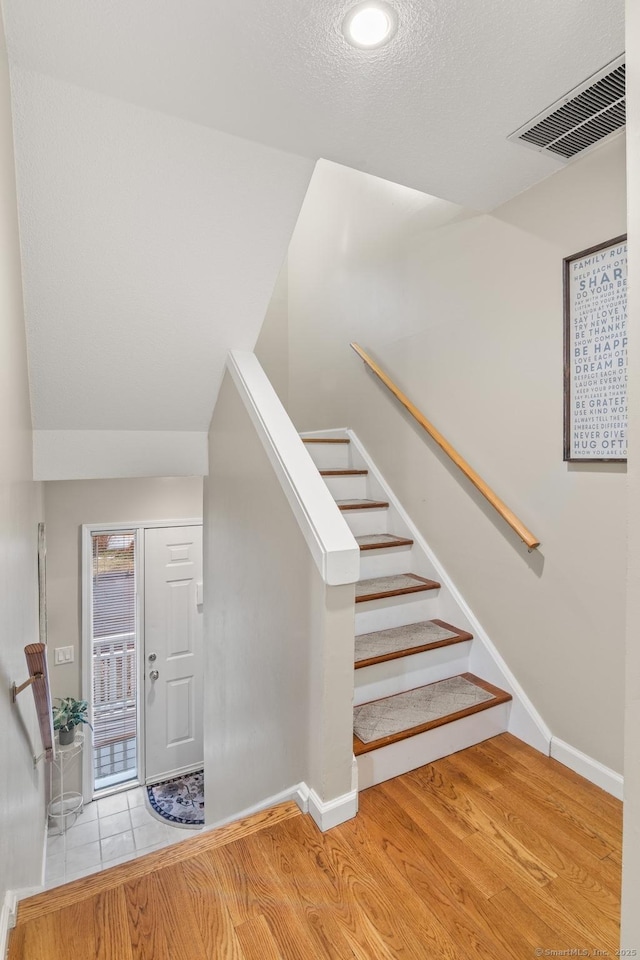 stairway with a textured ceiling and hardwood / wood-style floors