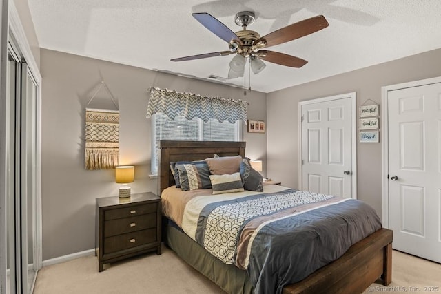 carpeted bedroom featuring ceiling fan and a textured ceiling