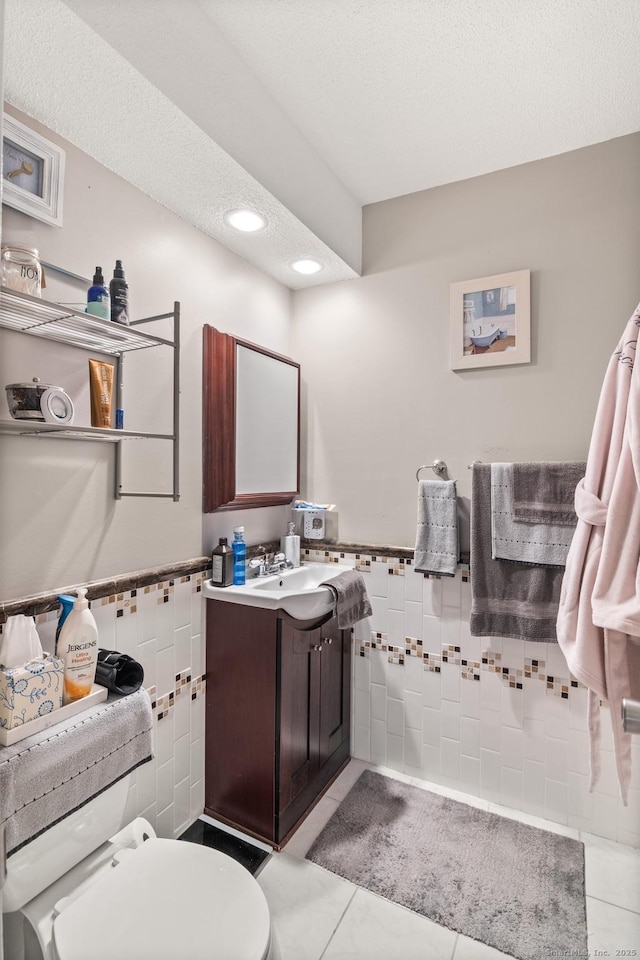 bathroom featuring toilet, vanity, tile walls, and tile patterned floors