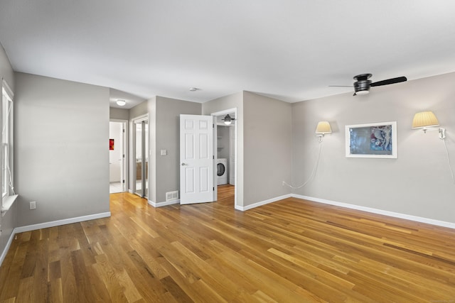 empty room with ceiling fan, washer / dryer, and wood-type flooring