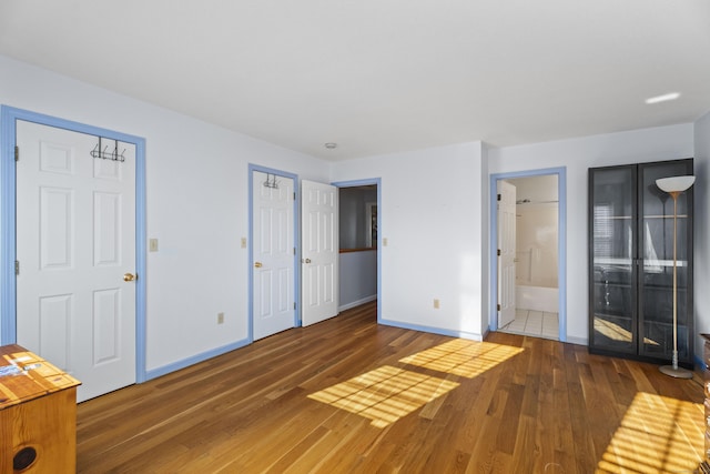 unfurnished bedroom with ensuite bathroom and dark hardwood / wood-style flooring