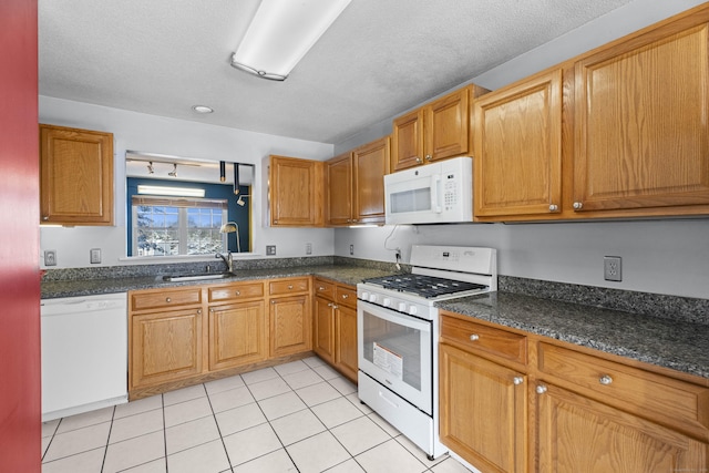 kitchen with sink, white appliances, light tile patterned floors, and a textured ceiling