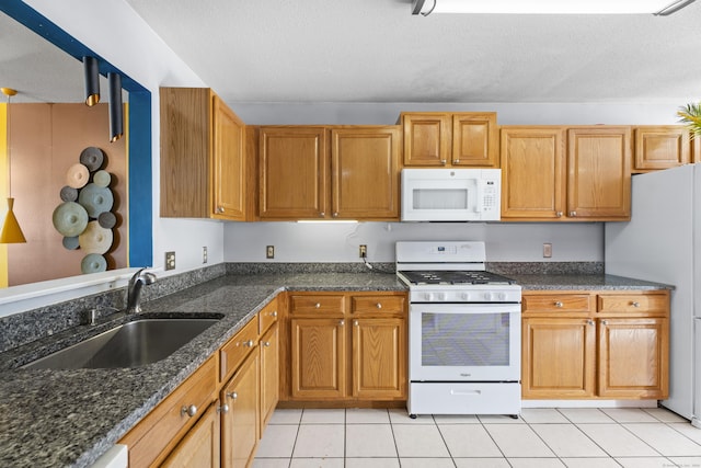 kitchen featuring white appliances, a textured ceiling, dark stone counters, sink, and light tile patterned flooring