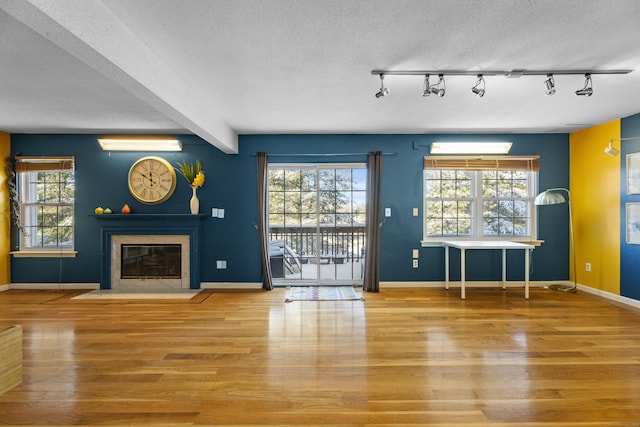 interior space featuring wood-type flooring, a textured ceiling, a wall mounted air conditioner, and beamed ceiling