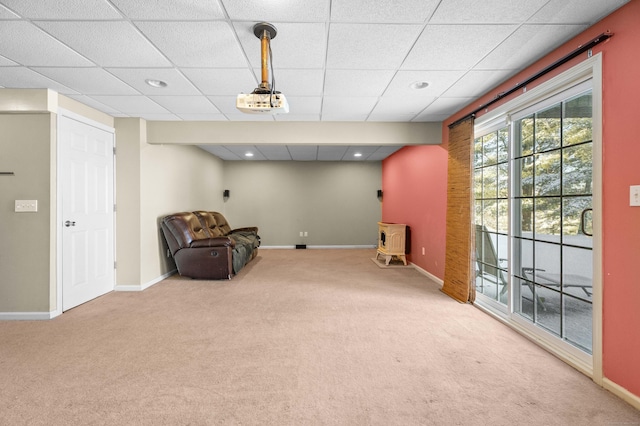 living area featuring a wood stove, carpet flooring, and a drop ceiling