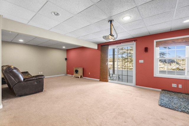 sitting room featuring a wood stove, a paneled ceiling, and carpet floors