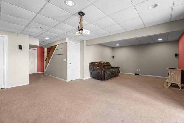 unfurnished room with a drop ceiling, carpet flooring, and a wood stove