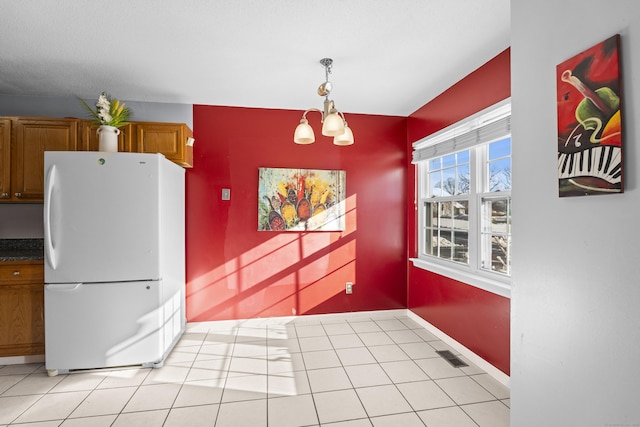 kitchen featuring white refrigerator, an inviting chandelier, light tile patterned floors, and hanging light fixtures