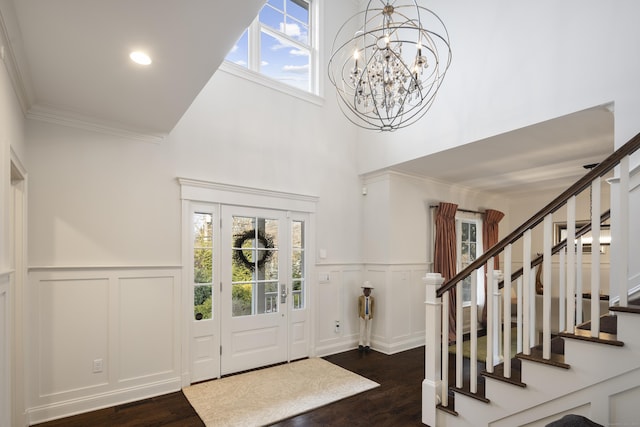 foyer entrance featuring dark wood-type flooring, a notable chandelier, and a towering ceiling