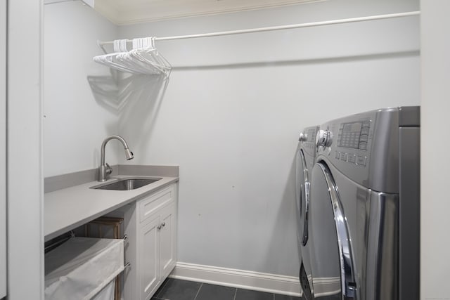 clothes washing area with sink, cabinets, ornamental molding, dark tile patterned floors, and washing machine and clothes dryer