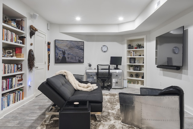 living room featuring built in shelves and hardwood / wood-style flooring