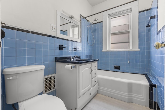 full bathroom with tiled shower / bath combo, vanity, tile walls, and toilet