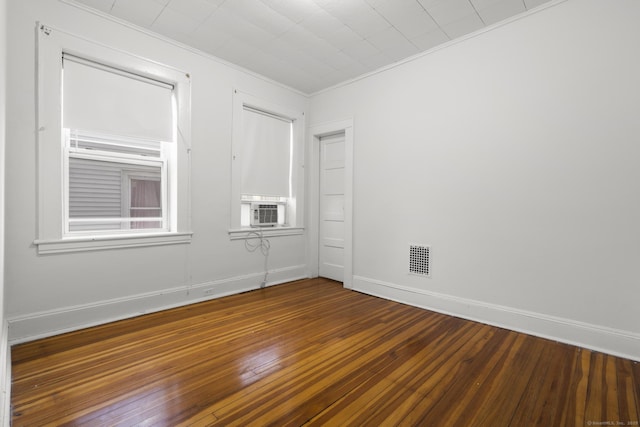 empty room with cooling unit, crown molding, and dark hardwood / wood-style floors