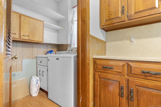 laundry room featuring washer / dryer, light hardwood / wood-style flooring, and cabinets