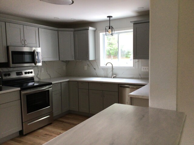 111 Pineville Rd, Killingly, CT 06241 - kitchen with appliances with stainless steel finishes, a sink, light wood finished floors, tasteful backsplash, and pendant lighting