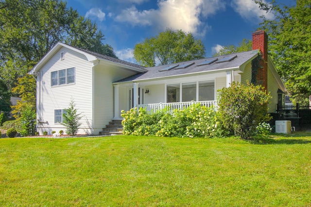 back of property with covered porch, a yard, and cooling unit