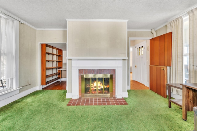 unfurnished living room featuring crown molding, a fireplace, dark carpet, and a textured ceiling