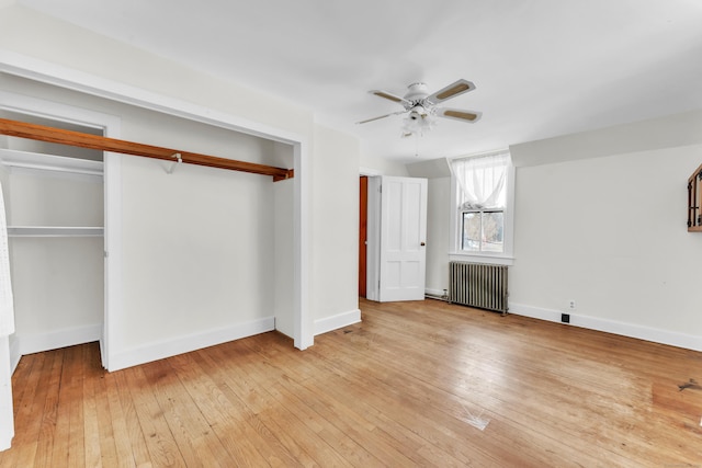 unfurnished bedroom with a closet, radiator, ceiling fan, and light hardwood / wood-style flooring