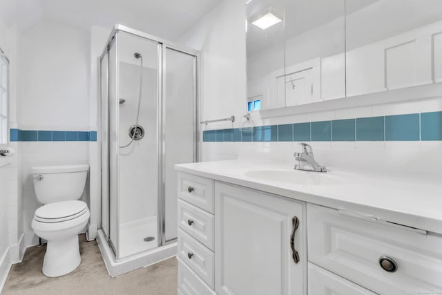 bathroom featuring a shower with door, vanity, tile walls, and toilet