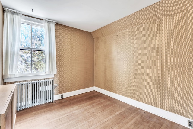 empty room featuring radiator heating unit and wood-type flooring