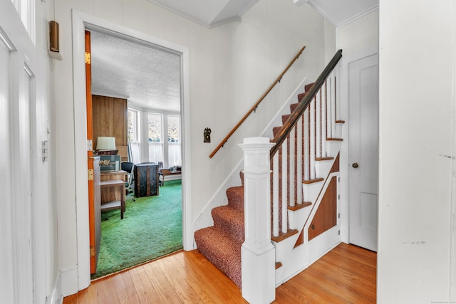 stairway featuring hardwood / wood-style floors and crown molding