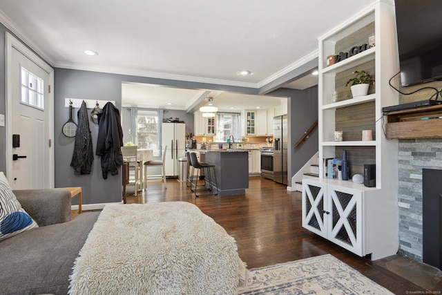 living room featuring dark hardwood / wood-style flooring, a stone fireplace, plenty of natural light, and crown molding