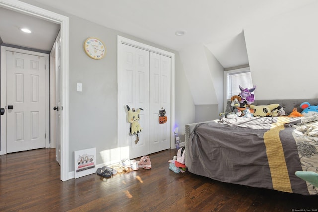 bedroom featuring dark hardwood / wood-style floors, vaulted ceiling, and a closet