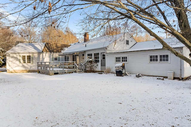 snow covered back of property featuring a wooden deck