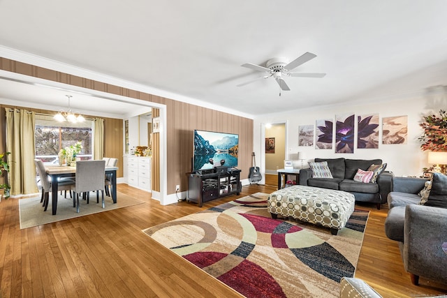 living room with ceiling fan with notable chandelier, wood-type flooring, and crown molding