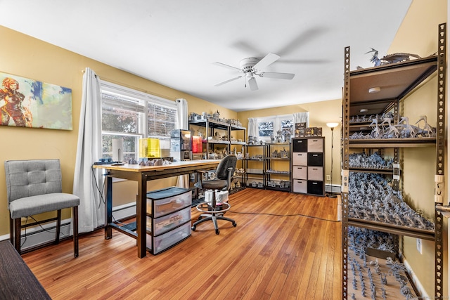 office space featuring ceiling fan, wood-type flooring, a wealth of natural light, and a baseboard heating unit