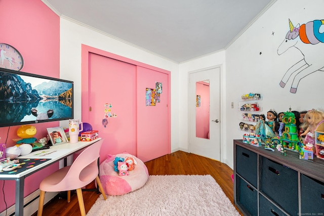 bedroom with baseboard heating, a closet, dark hardwood / wood-style flooring, and crown molding