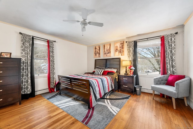 bedroom with ceiling fan, a baseboard heating unit, hardwood / wood-style flooring, and ornamental molding