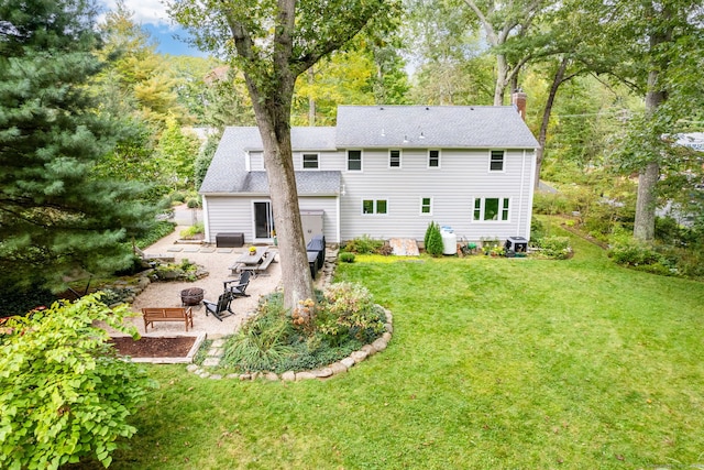 rear view of property featuring roof with shingles, a patio, a chimney, a lawn, and an outdoor fire pit