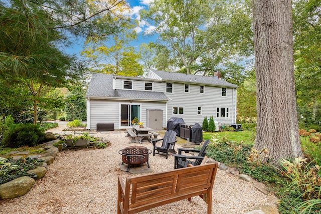 back of property with a patio area, an outdoor fire pit, a chimney, and roof with shingles