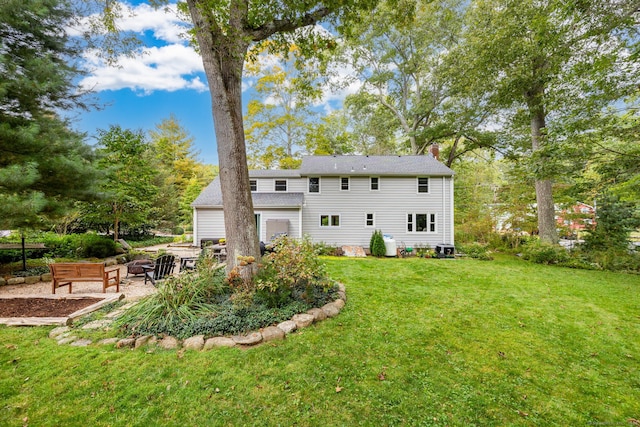 back of house with a patio area, a chimney, and a yard