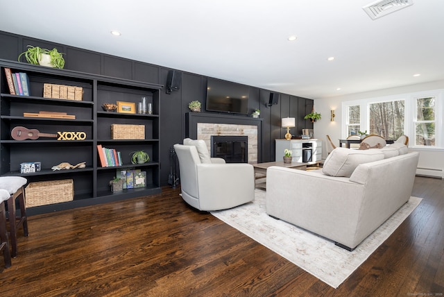 living room with a fireplace, a baseboard radiator, recessed lighting, visible vents, and dark wood-type flooring