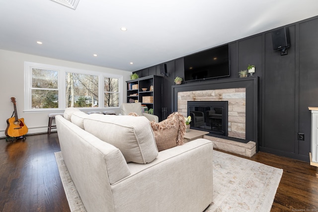 living area with a stone fireplace, dark wood finished floors, and recessed lighting