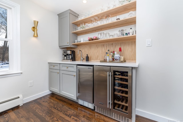 bar featuring wine cooler, a baseboard heating unit, baseboards, freestanding refrigerator, and indoor wet bar