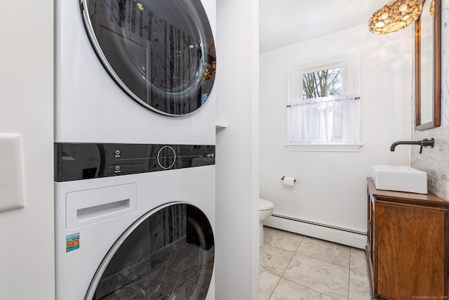 laundry room featuring marble finish floor, stacked washer and dryer, baseboard heating, and a sink