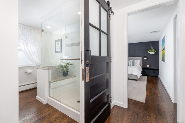 ensuite bathroom featuring baseboards, visible vents, wood finished floors, a shower stall, and a baseboard heating unit