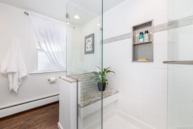 full bathroom with wood finished floors, baseboard heating, a tile shower, and recessed lighting