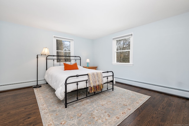 bedroom with a baseboard heating unit, multiple windows, and wood finished floors