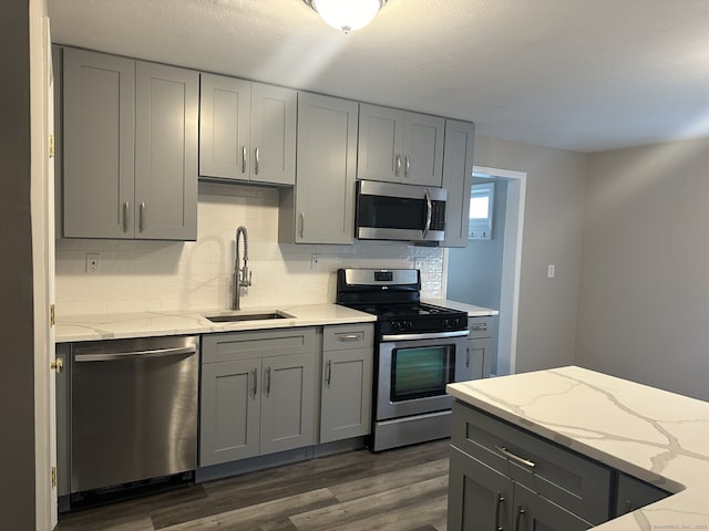 kitchen featuring light stone countertops, sink, appliances with stainless steel finishes, and gray cabinets