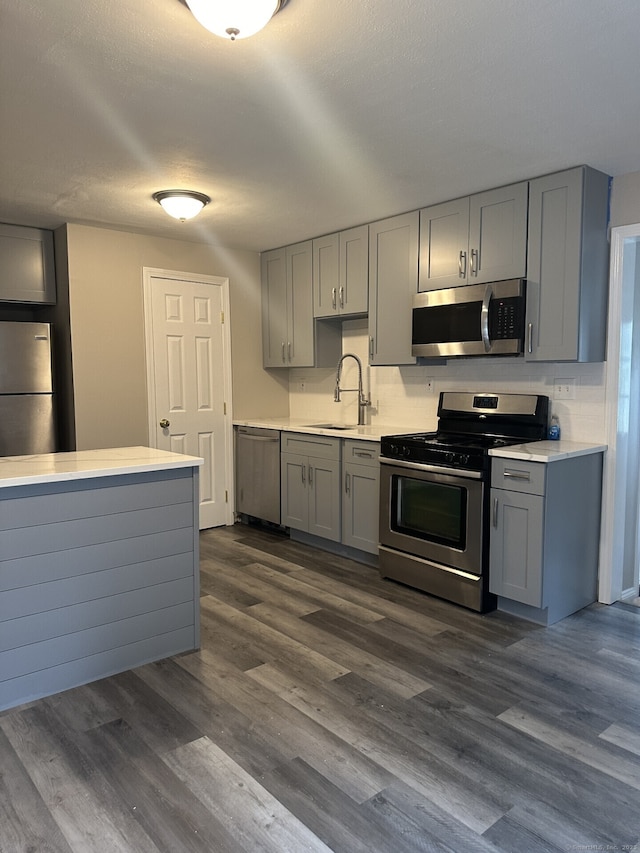 kitchen with sink, stainless steel appliances, dark wood-type flooring, and gray cabinets