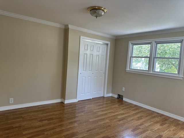 unfurnished bedroom featuring a closet, ornamental molding, and dark hardwood / wood-style flooring